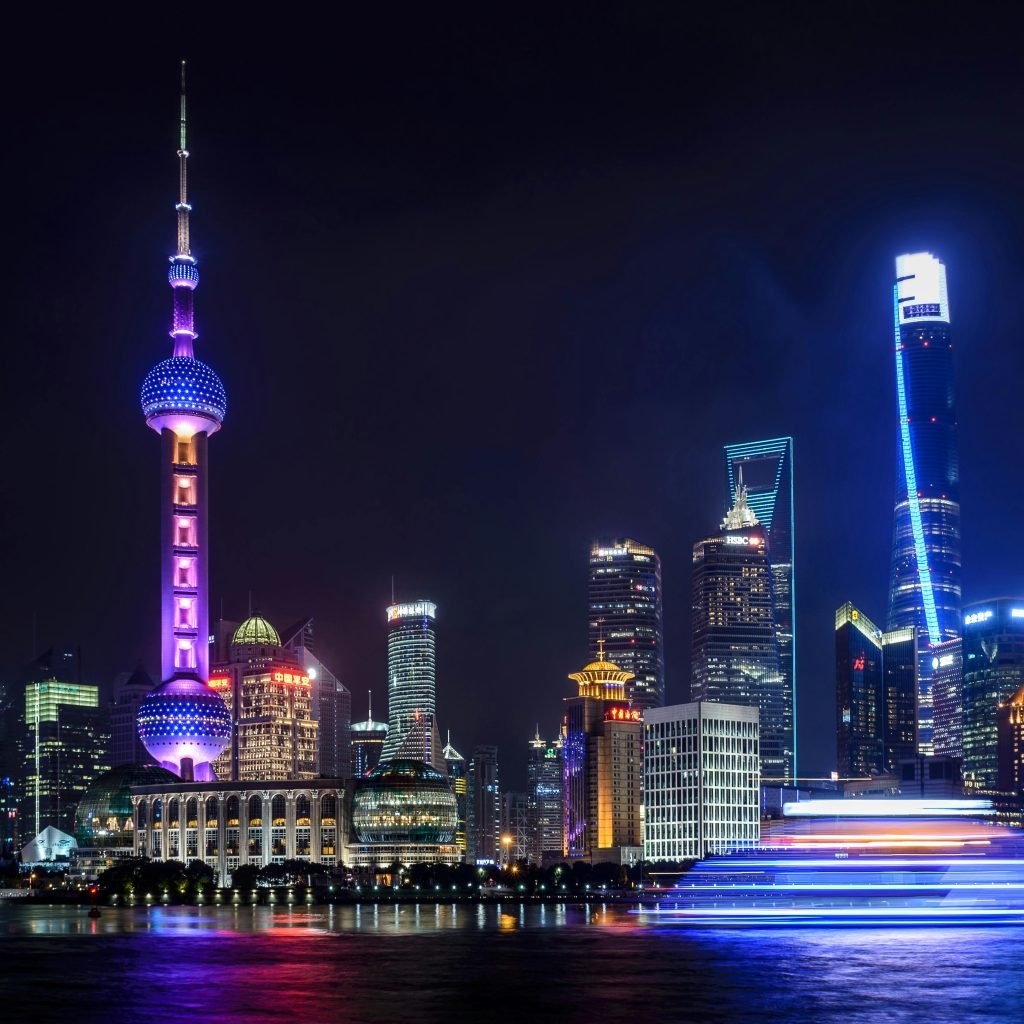 Stunning night view of Shanghai skyline with illuminated skyscrapers and the Oriental Pearl Tower reflecting in the water.